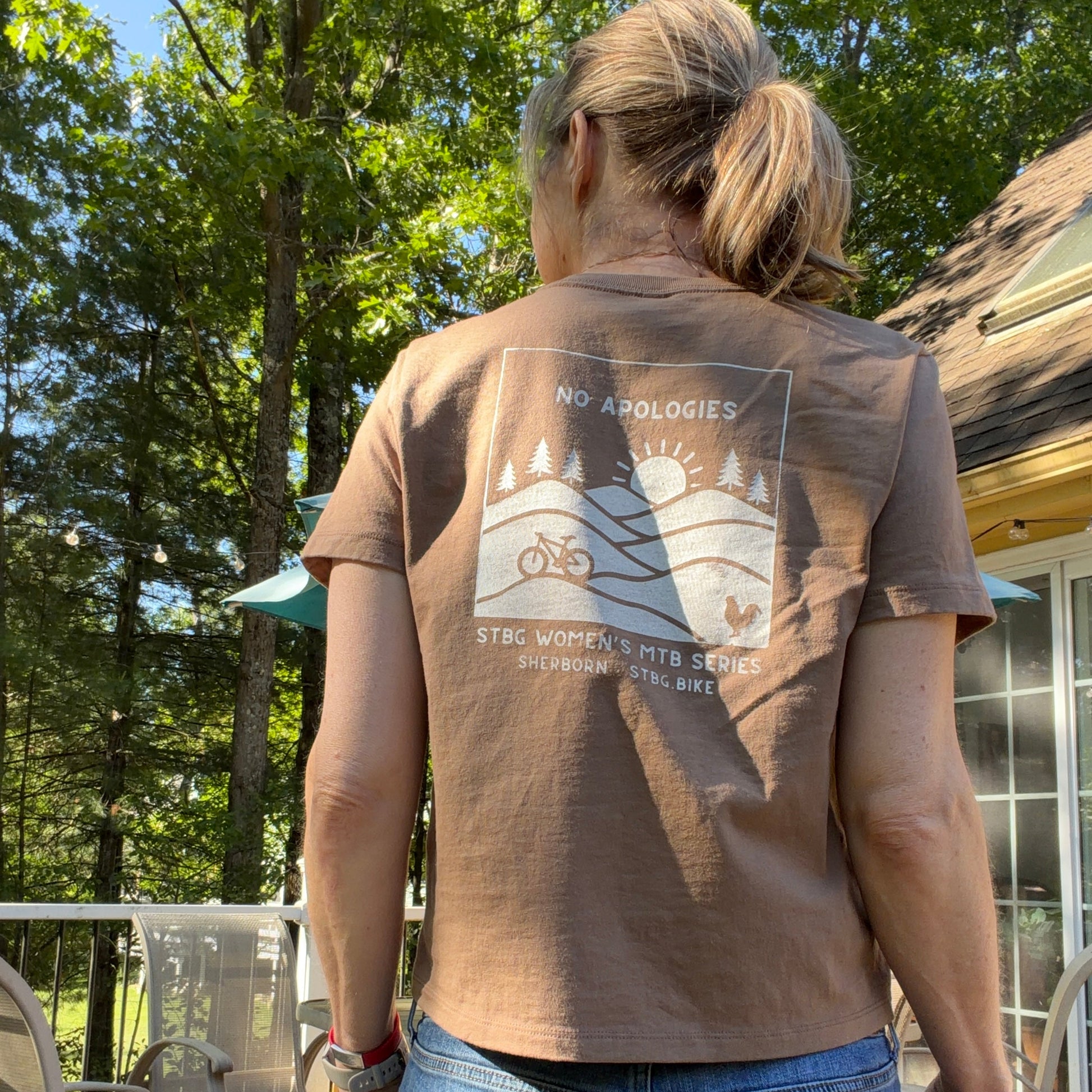 A woman wearing a brown t-shirt which reads "No Apologies"